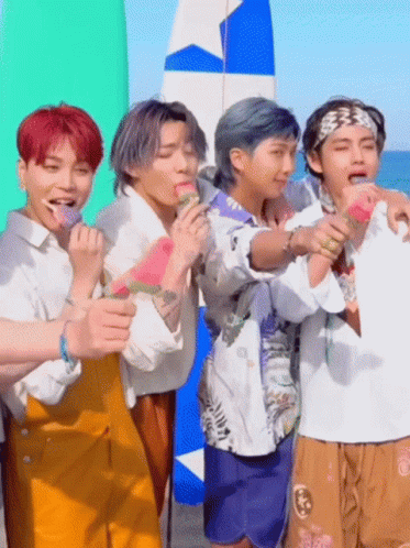 A Group Of Young Men Are Standing On A Beach Eating Watermelons . GIF