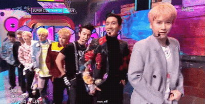 A Group Of Young Men Are Standing On A Stage With A Sign That Says Super Cup GIF