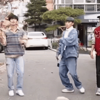 A Group Of Young Men Are Standing On A Street . GIF