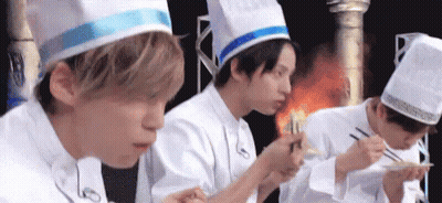 A Group Of Young Men In Chef Hats Are Eating Food With Chopsticks . GIF