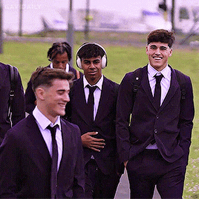 A Group Of Young Men In Suits And Ties Are Walking Together GIF