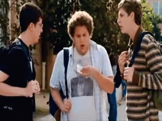 A Group Of Young Men Standing On A Sidewalk Talking To Each Other GIF