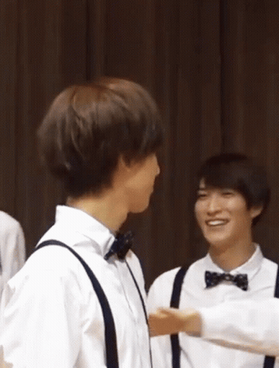 A Group Of Young Men Wearing Bow Ties And Suspenders Are Hugging GIF