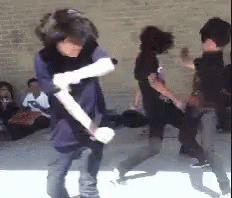 A Group Of Young People Are Dancing In Front Of A Brick Wall GIF