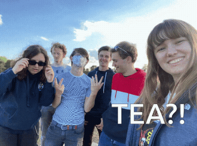 A Group Of Young People Are Posing For A Picture And One Of Them Is Wearing A Mask With The Word Tea On It GIF