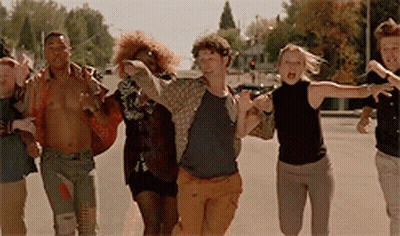 A Group Of Young People Are Running Down A Street GIF