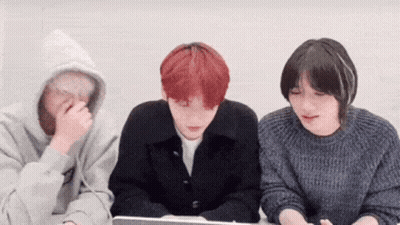 A Group Of Young People Are Sitting Around A Table Looking At A Laptop . GIF