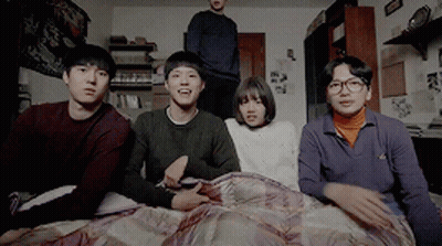 A Group Of Young People Are Sitting On A Bed Looking At Something GIF
