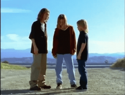 a group of young people are standing on a dirt road .