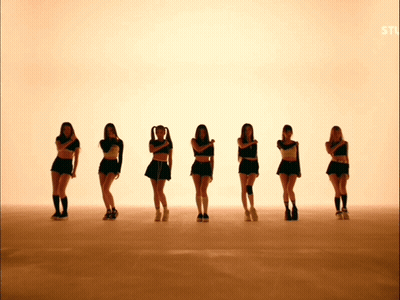 A Group Of Young Women Are Standing In A Row With Their Arms Crossed GIF