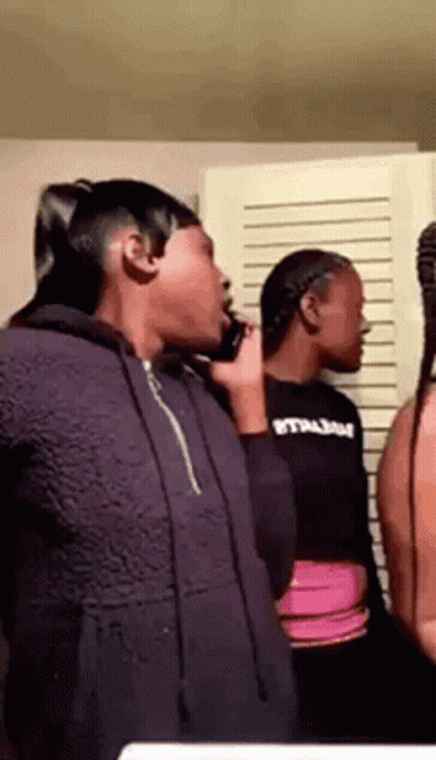 A Group Of Young Women Are Standing Next To Each Other In A Room Talking On Cell Phones . GIF