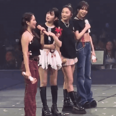 A Group Of Young Women Are Standing On A Stage Holding Microphones . GIF