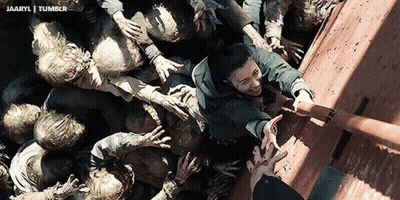 A Group Of Zombies Are Reaching For A Man 'S Hand In A Scene From A Movie GIF