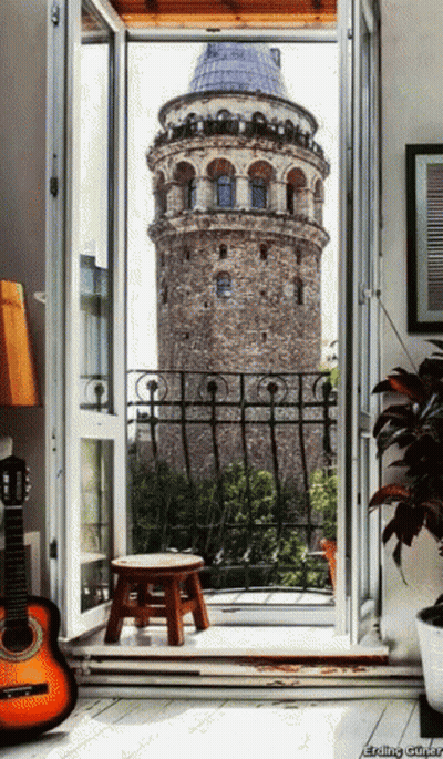 A Guitar Sits On The Floor In Front Of A Balcony With A View Of A Tower GIF