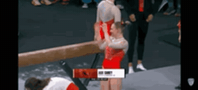 A Gymnast Is Doing A Trick On A Balance Beam While Another Gymnast Looks On . GIF