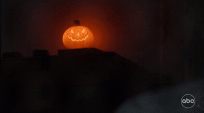 A Halloween Pumpkin With A Face Carved Into It Is Lit Up In The Dark . GIF