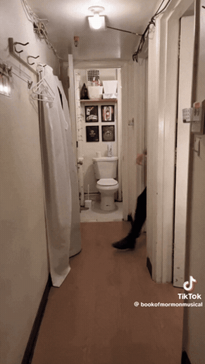 A Hallway With A Toilet And A Sign That Says Bookofmormonmusical GIF
