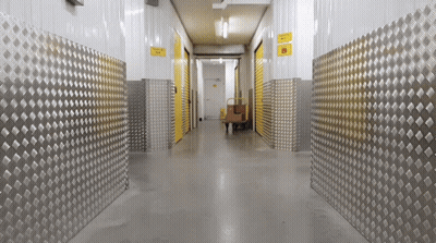 A Hallway With Metal Walls And A Yellow Sign That Says ' Warehouse ' On It GIF