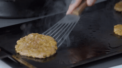 A Hamburger Patty Is Being Cooked On A Grill GIF
