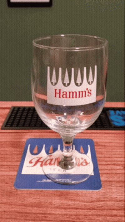 A Hamm 'S Glass Sits On A Blue And White Coaster GIF