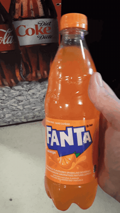 A Hand Is Holding A Bottle Of Orange Fanta Soda GIF