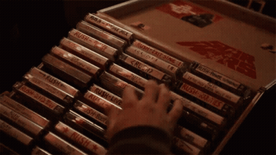 A Hand Is Holding A Cassette Tape That Says Rush On It GIF