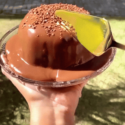 A Hand Is Holding A Glass Bowl Of Chocolate Cake GIF
