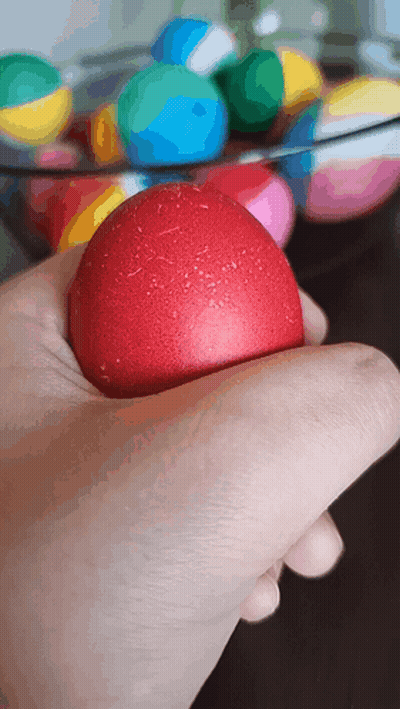 A Hand Is Holding A Red Ball In Front Of A Bowl Of Balls GIF