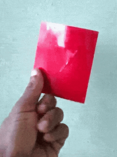 A Hand Is Holding A Red Piece Of Paper With A White X On It GIF