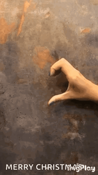 A Hand Is Making A Heart Shape With Its Fingers On A Concrete Surface . GIF