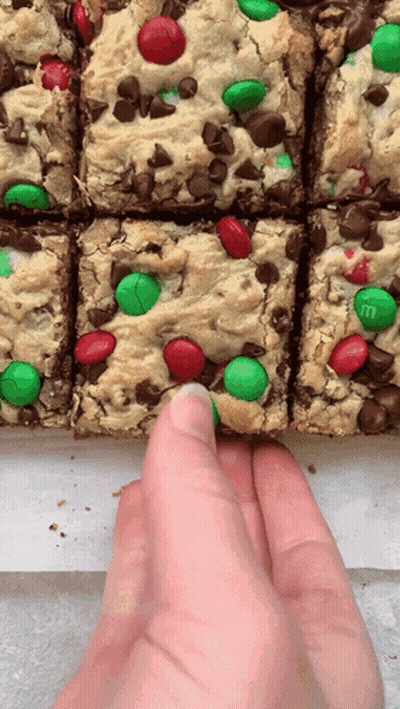 A Hand Is Reaching For A Cookie Bar With M & M 'S GIF
