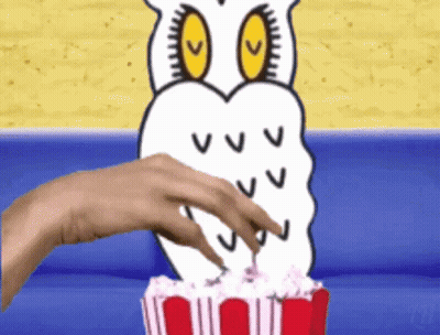 A Hand Reaches Into A Bucket Of Popcorn With An Owl On It GIF