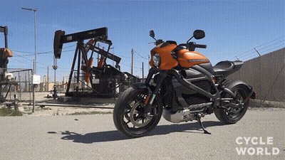 A Harley Davidson Motorcycle Is Parked On The Side Of The Road In Front Of An Oil Pump GIF
