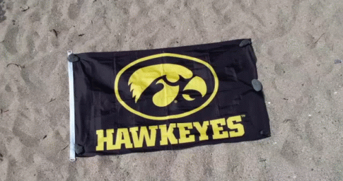 A Hawkeyes Flag Is Laying On The Sand GIF