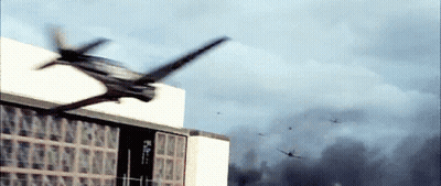 A Helicopter Is Flying Over A Building With Smoke Coming Out Of The Window GIF