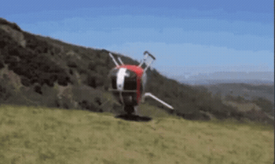A Helicopter Is Flying Over A Grassy Hillside With Trees In The Background GIF