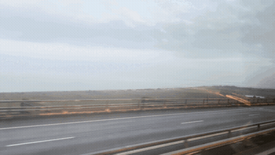 A Highway With A Bridge In The Background And A Cloudy Sky GIF