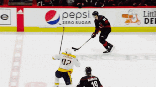 A Hockey Game Is Being Played In Front Of An Advertisement For Geico And Verizon GIF