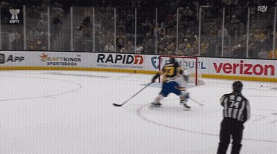 A Hockey Game Is Being Played On A Rink With Advertisements For Rapid7 And Verizon GIF