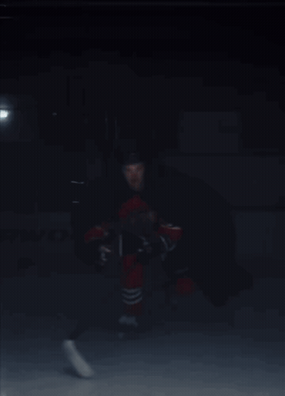 A Hockey Player In A Red And Black Uniform Is Holding A Hockey Stick GIF