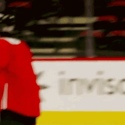 A Hockey Player In A Red Jersey Is Standing On The Ice In Front Of A Banner . GIF