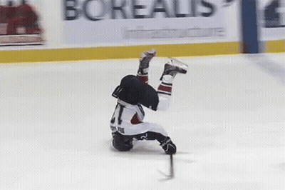 A Hockey Player Is Falling On His Back On The Ice While Holding A Puck . GIF