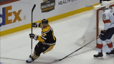 A Hockey Player Is Holding A Puck In Front Of A Fedex Sign GIF
