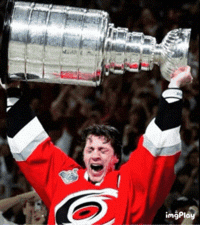 A Hockey Player Is Holding Up A Trophy In His Hands GIF