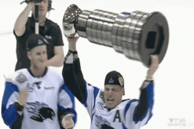 A Hockey Player Is Holding Up A Trophy While Another Player Watches . GIF