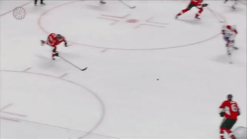 A Hockey Player Is Laying On The Ice While Another Player Stands Nearby GIF