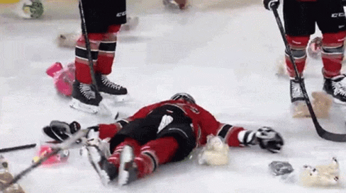 A Hockey Player Is Laying On The Ice With His Skates On His Head GIF