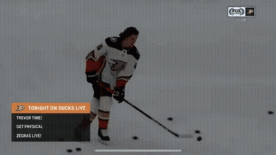 A Hockey Player Is Skating In The Snow With A Puck And A Stick . GIF