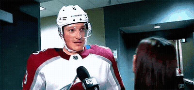 A Hockey Player Is Talking Into A Microphone While Standing Next To A Woman . GIF