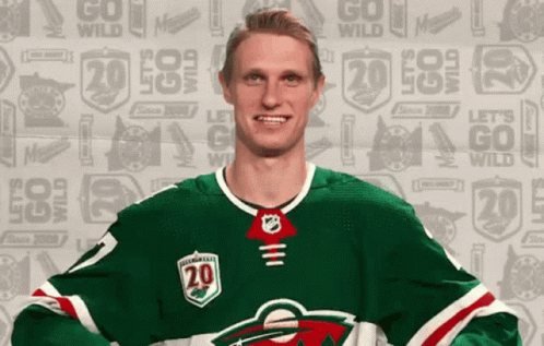 A Hockey Player Is Wearing A Green Jersey With The Number 20 On It GIF